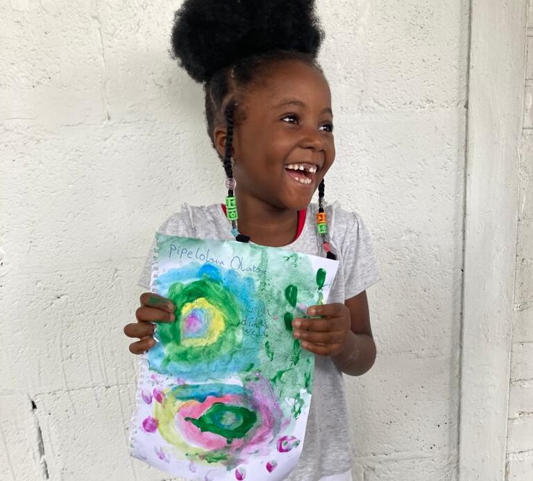 Child laughing with a painted picture she made