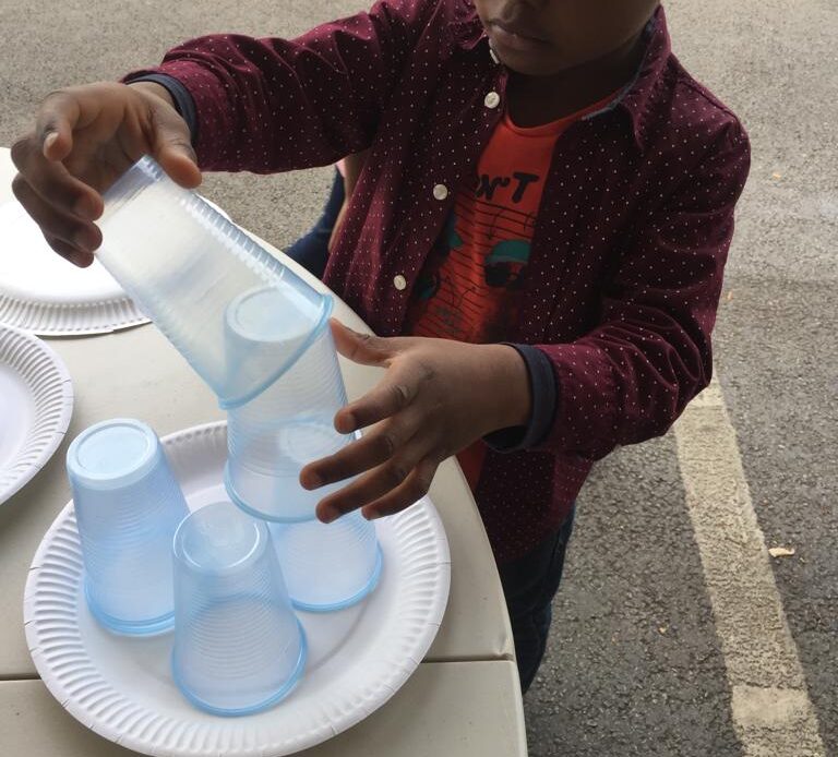 Boy concentrating on building a paper plate and plastic cup tower